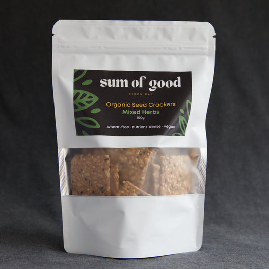 Packaged organic seed crackers with 'sum of good' branding on a dark background