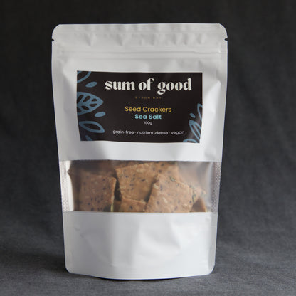 Packaged seed crackers with 'sum of good' label on a dark background