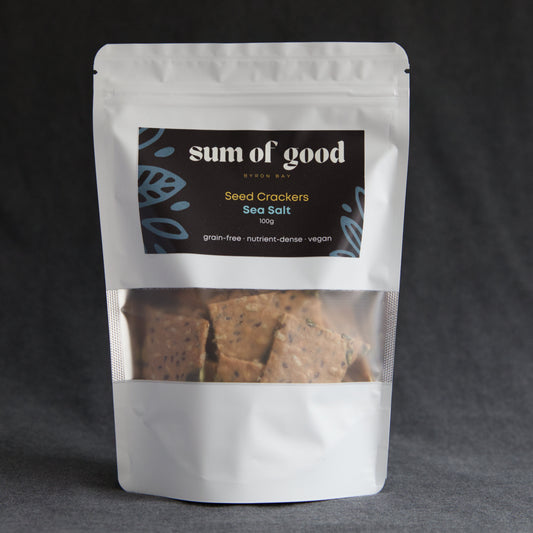 Packaged seed crackers with 'sum of good' label on a dark background